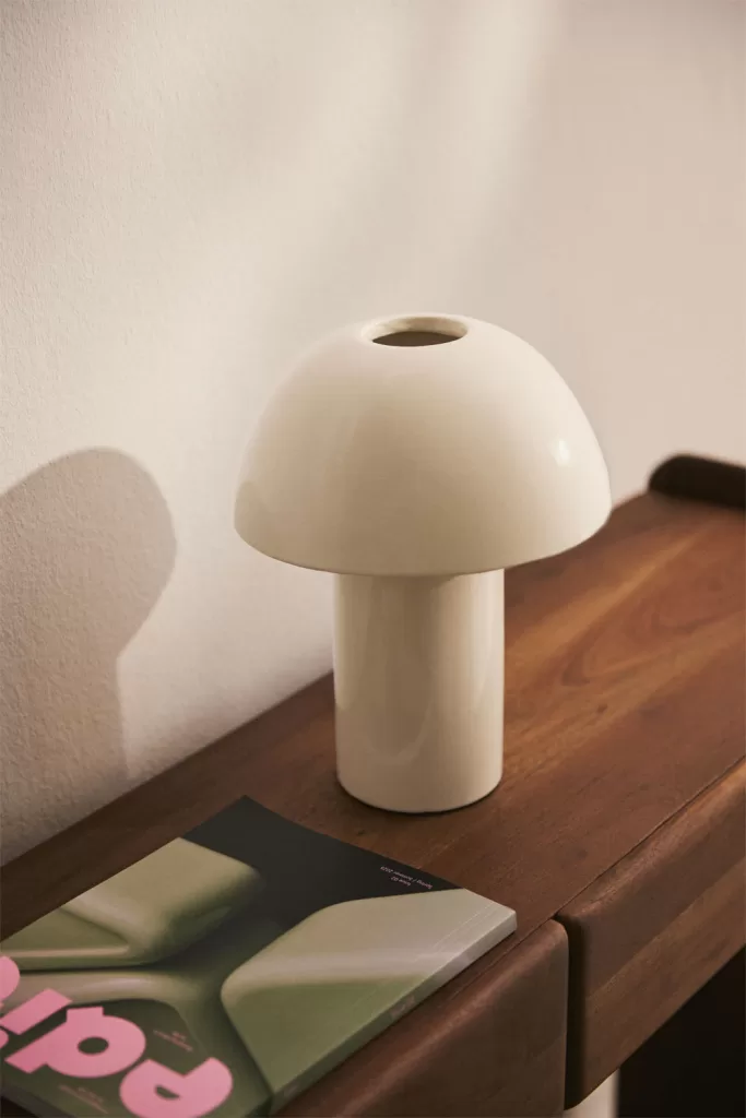 Candeeiro de mesa branco sobre um aparador de madeira, perfeito para a iluminação de uma sala sem teto falso.