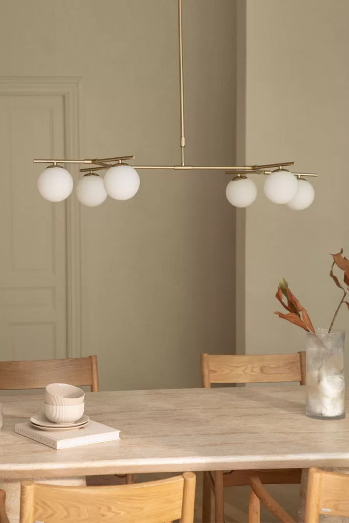 Candeeiro de teto dourado com globos brancos sobre a mesa de jantar, uma ótima solução de iluminação para salas sem teto falso.