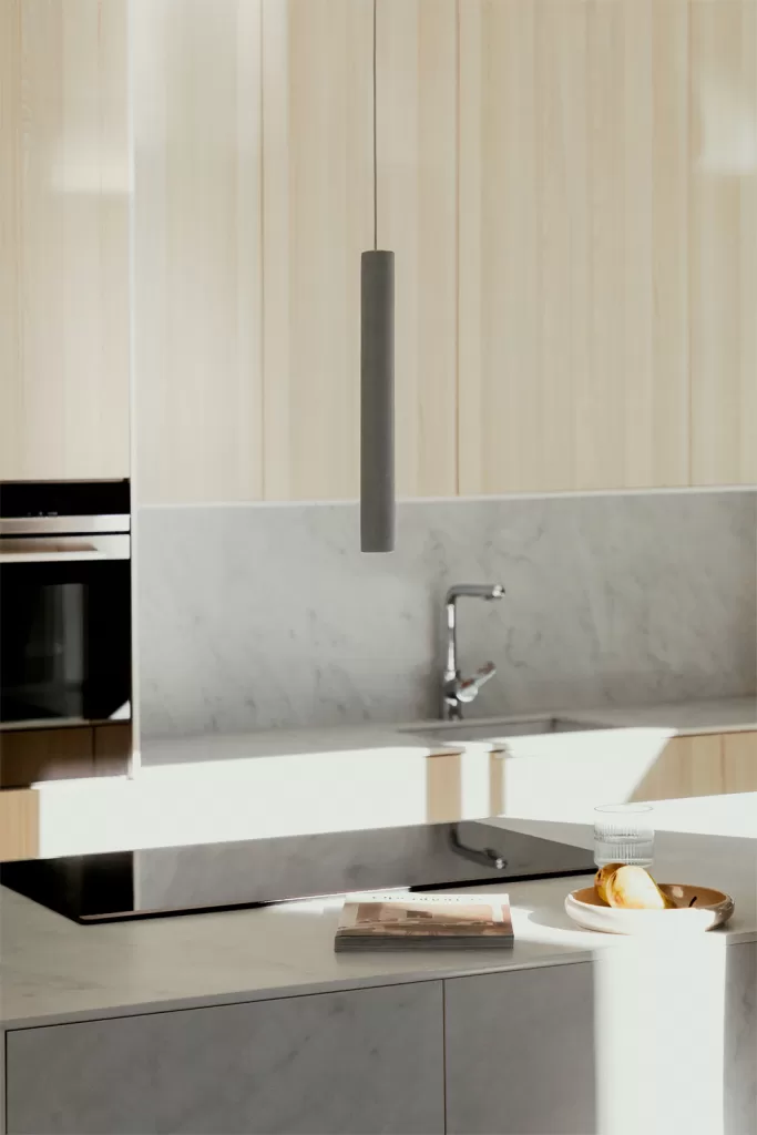 Helle zweifarbige Küche mit einer Kücheninsel, beigefarbenen Schränken und stilvoller Pendelleuchte