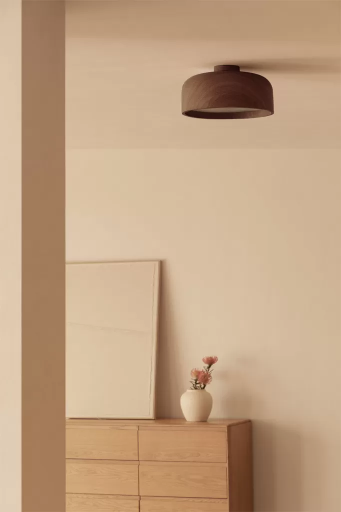 Plafom castanho acima de uma cómoda de madeira num ambiente minimalista, uma excelente opção de iluminação para salas sem teto de pladur.