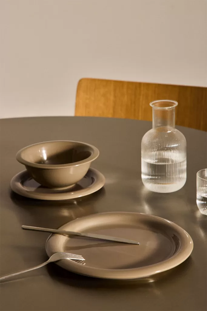 Erdfarbenes Geschirr auf einem dunklen Esstisch, passend zu einer eleganten und einladenden zweifarbigen Küche