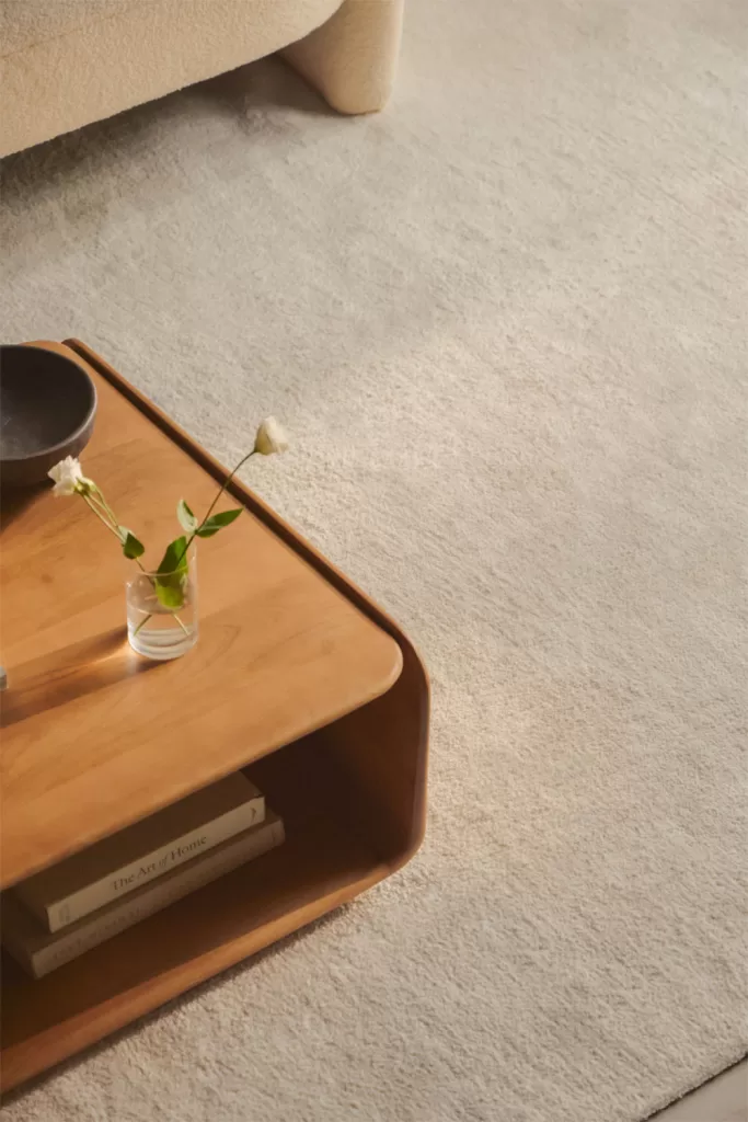 Como decorar um loft com tapete claro, mesa de apoio em madeira e sofá de textura suave