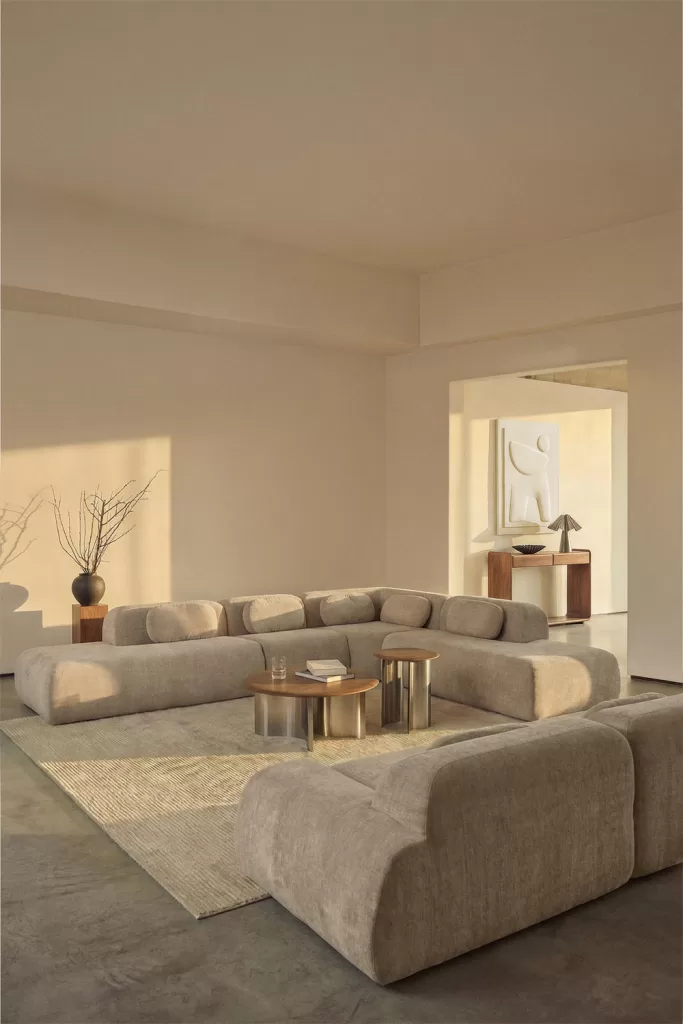 Como decorar um loft com sofá modular cinzento, tapete bege e mesas redondas numa sala aberta