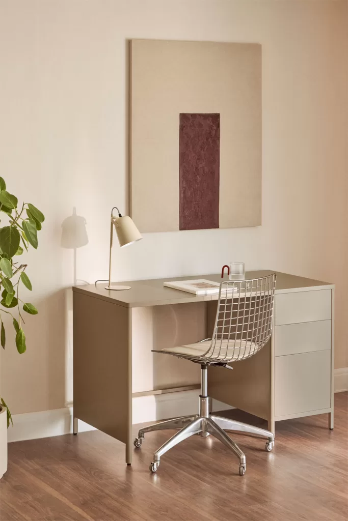 Escritorio blanco con silla cromada para postura correcta ordenador y monitor a altura adecuada en despacho cálido