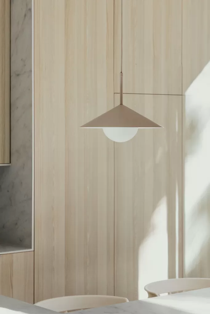 Decorar cocina pequeña con lámpara de techo beige sobre mesa clara y pared de madera luminosa
