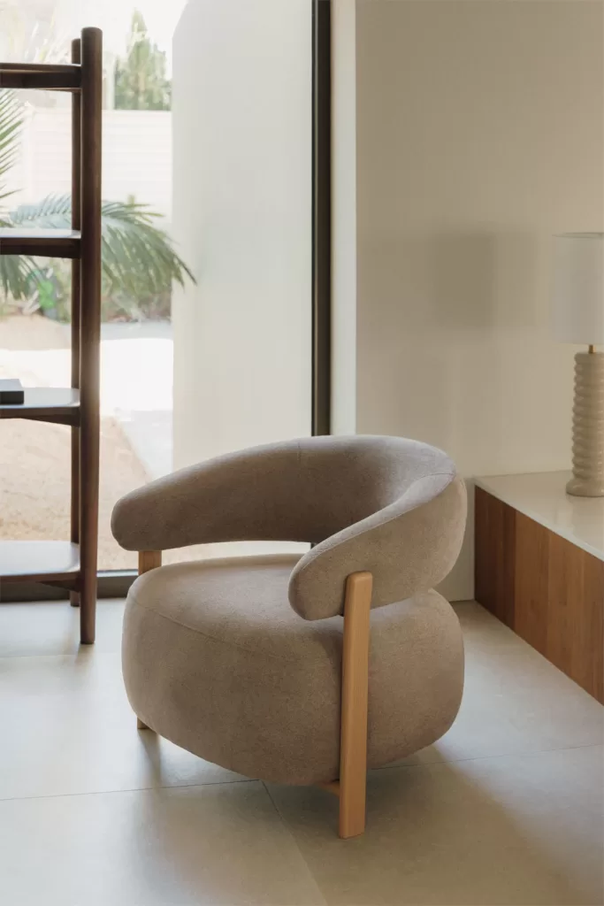 Butaca beige de diseño para pausas activas y postura correcta ordenador en rincón luminoso con mesa auxiliar
