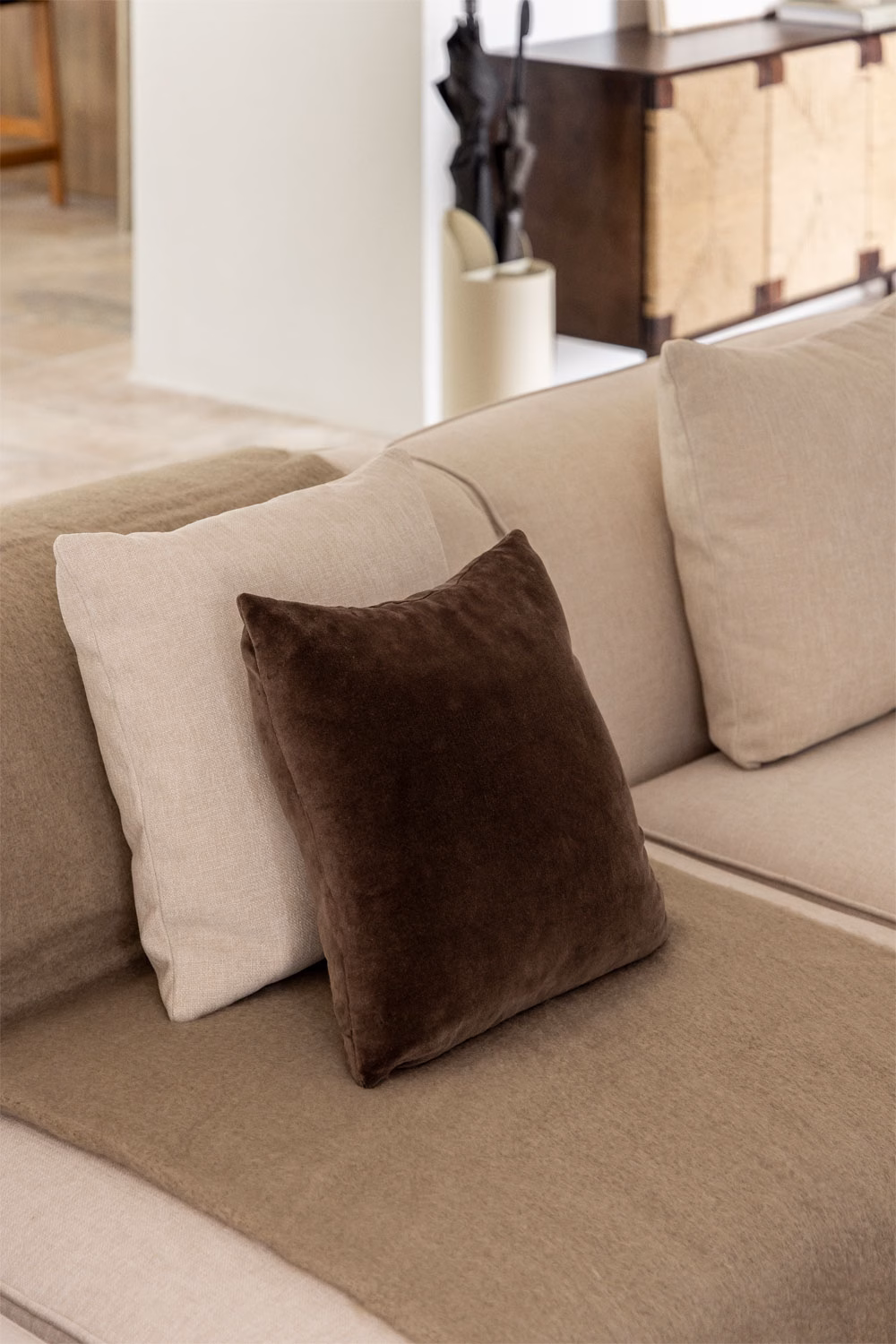 Coussins marron foncé et marron clair sur un canapé beige, illustrant parfaitement la règle des couleurs avec des tons terreux.